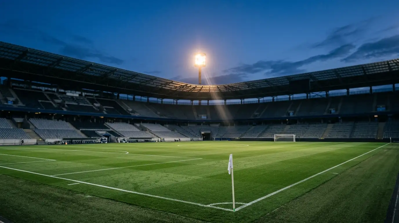 Editorial-Sportfoto einer Anzeigetafel mit Lichteffekten bei Nacht in einem Stadion, Fokus auf das grüne Spielfeld im Vordergrund, ohne Logos, Flaggen oder erkennbare Buchstaben